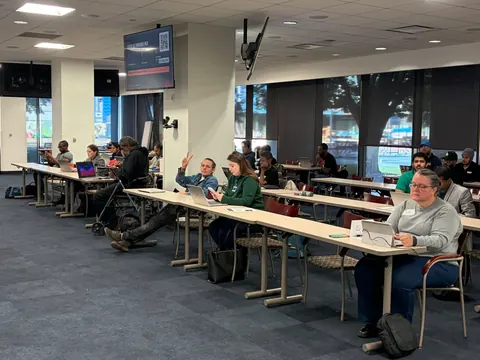 Builders at laptop-filled tables across the room at One Ford Place