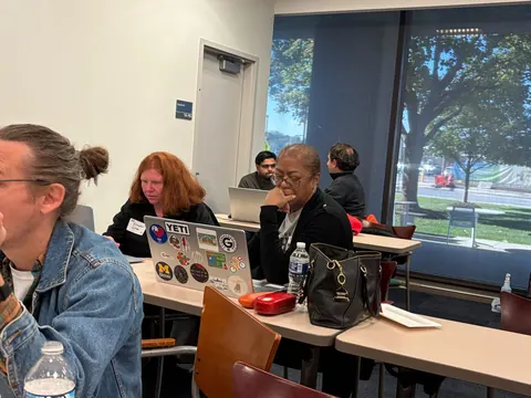 Builders working on laptops at tables beside the windows