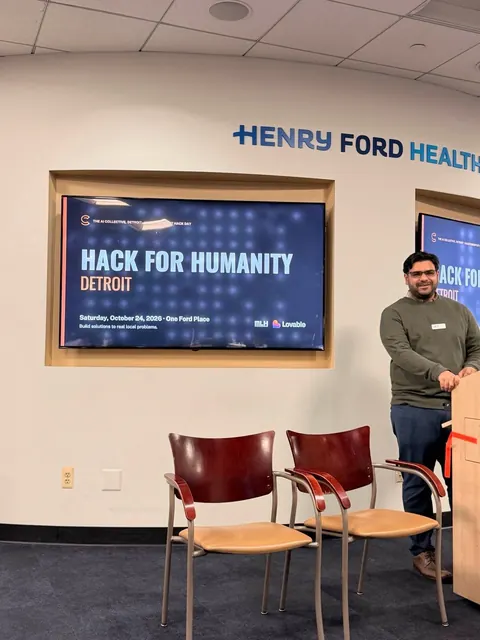 An organizer at the podium beside the Hack for Humanity Detroit opening slide
