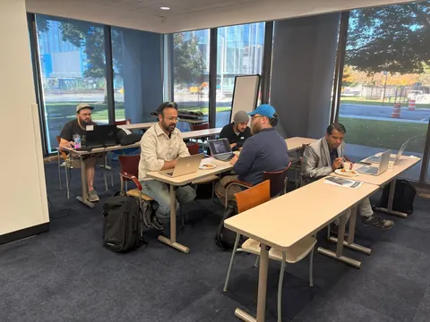 Builders collaborating at laptop-filled tables during the working lunch