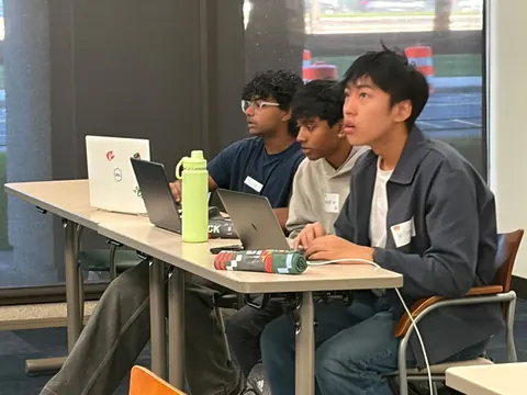 Three builders seated together at laptops during the hackathon